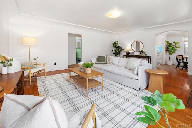 living area featuring arched walkways, baseboards, and light wood-type flooring