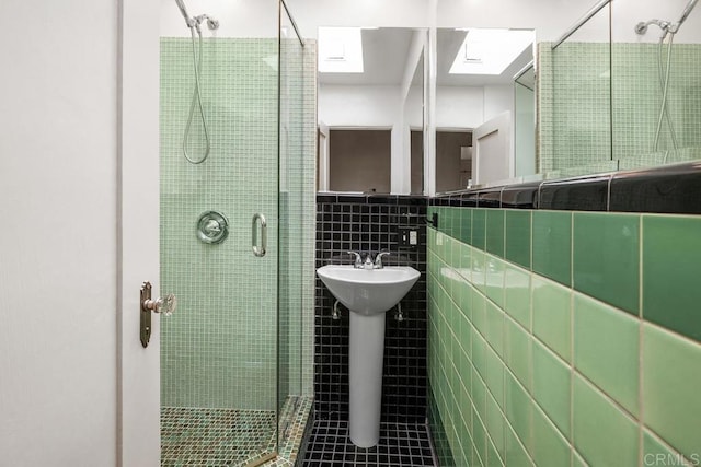 bathroom featuring a sink, tile patterned floors, tile walls, a skylight, and a stall shower