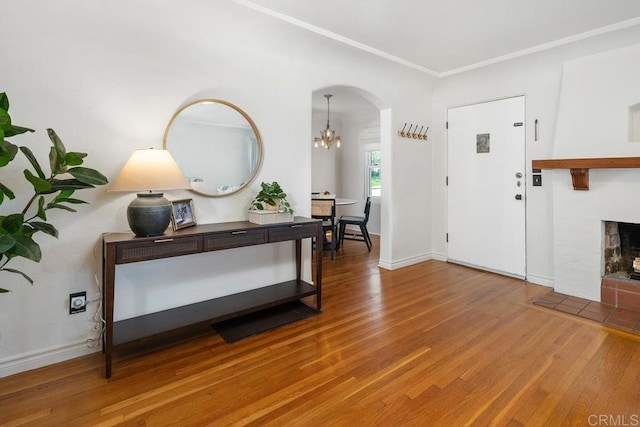 foyer with arched walkways, baseboards, wood finished floors, and a fireplace