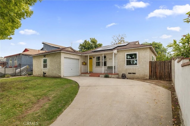 ranch-style house featuring a front lawn, a garage, roof mounted solar panels, covered porch, and driveway