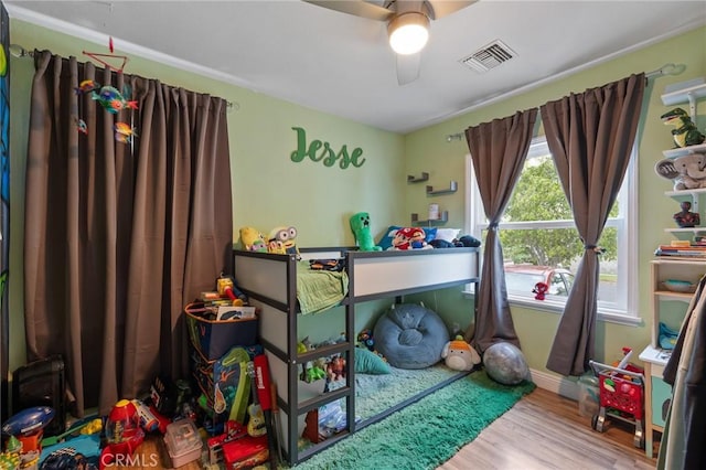 bedroom with ceiling fan, wood finished floors, and visible vents