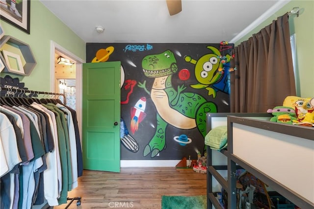 interior space with baseboards, a ceiling fan, and wood finished floors