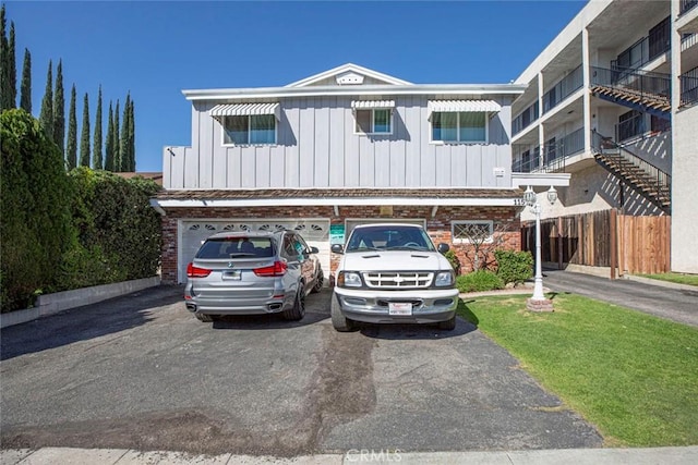 townhome / multi-family property featuring an attached garage, aphalt driveway, and board and batten siding