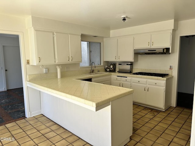 kitchen featuring black gas stovetop, a sink, white cabinetry, a peninsula, and under cabinet range hood