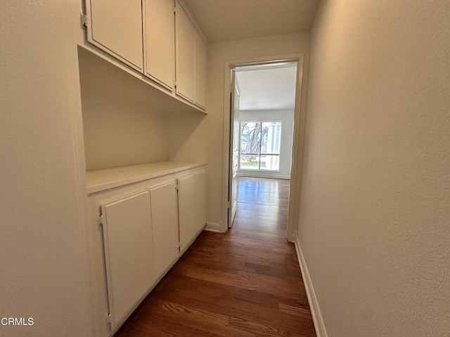 corridor featuring baseboards and wood finished floors