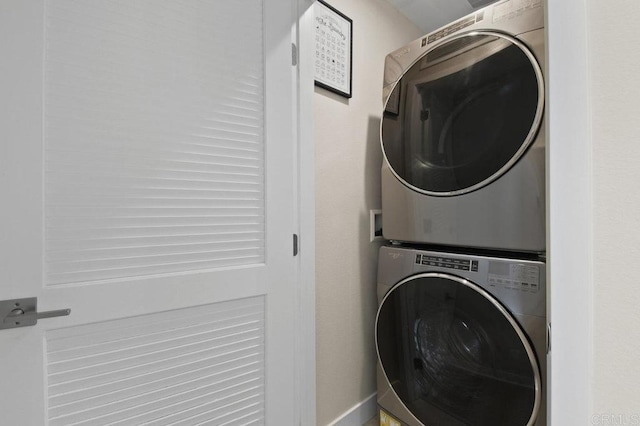 washroom featuring baseboards, laundry area, and stacked washer and clothes dryer