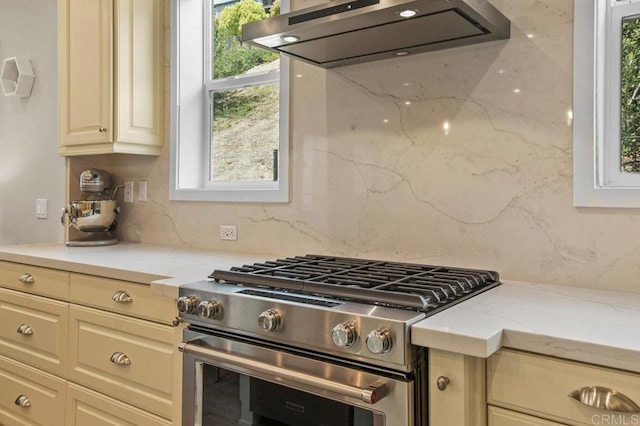 kitchen featuring range hood, tasteful backsplash, stainless steel range, and a wealth of natural light