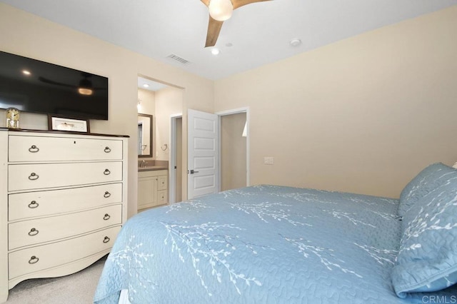 carpeted bedroom with a sink, ceiling fan, ensuite bath, and visible vents