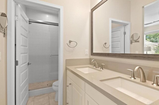 full bathroom with toilet, double vanity, a sink, and a shower stall