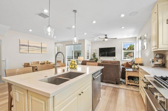 kitchen featuring a sink, stainless steel appliances, cream cabinets, light wood-type flooring, and visible vents