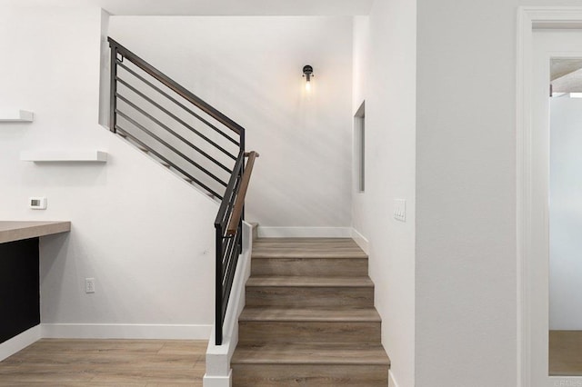 staircase featuring baseboards and wood finished floors