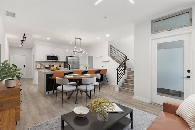 living area featuring recessed lighting, baseboards, light wood finished floors, and stairs