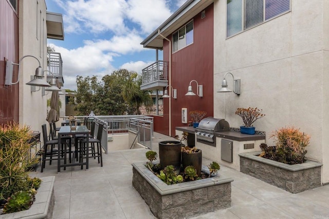view of patio featuring an outdoor kitchen, a balcony, outdoor wet bar, and a grill