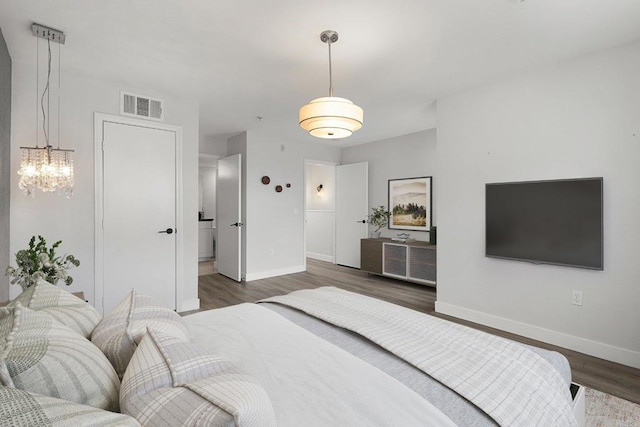 bedroom with an inviting chandelier, baseboards, wood finished floors, and visible vents