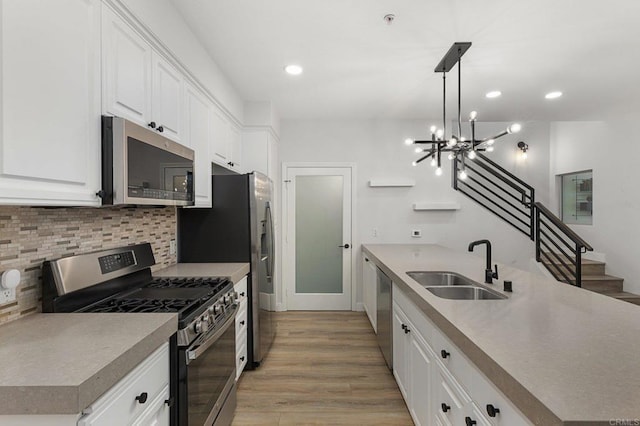 687 S Coast Highway 101 Unit 232, Encinitas, CA 92024 - kitchen with stainless steel appliances, light wood-type flooring, tasteful backsplash, a chandelier, and white cabinetry