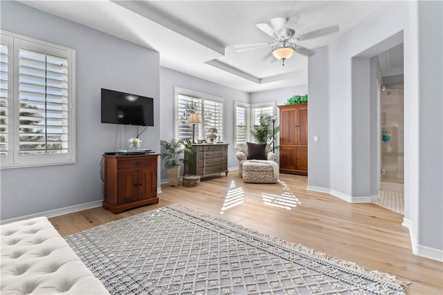 living area featuring light wood-style floors, baseboards, and a ceiling fan
