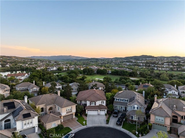 aerial view at dusk featuring a mountain view and a residential view
