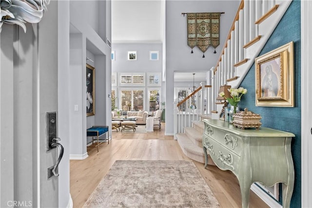 entrance foyer featuring baseboards, stairs, wood finished floors, and a towering ceiling