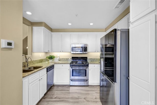 2641 Dunstan Dr, Tustin, CA 92782 - kitchen featuring white cabinets, appliances with stainless steel finishes, a sink, and light stone counters