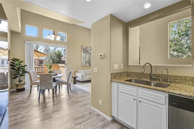 2641 Dunstan Dr, Tustin, CA 92782 - kitchen with dishwasher, a sink, light stone counters, a notable chandelier, and white cabinetry