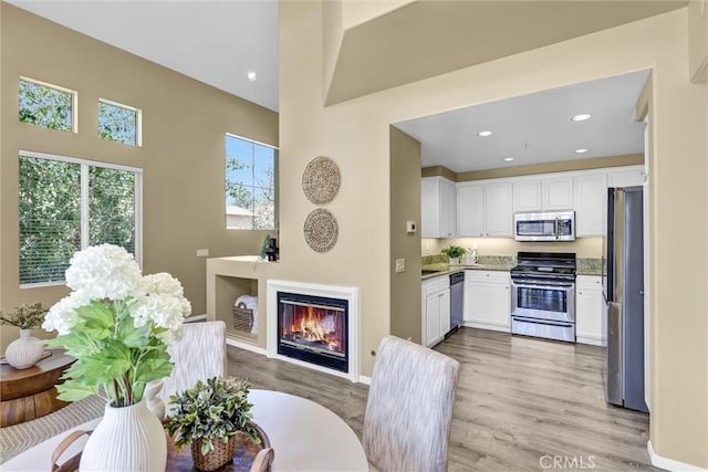 2641 Dunstan Dr, Tustin, CA 92782 - interior space featuring a glass covered fireplace, recessed lighting, baseboards, and light wood-type flooring