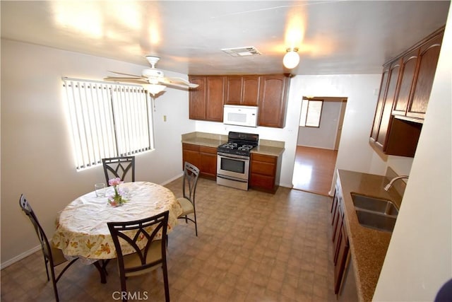 kitchen featuring visible vents, ceiling fan, white microwave, a sink, and gas stove