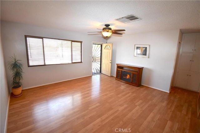 unfurnished living room with visible vents, baseboards, a textured ceiling, a ceiling fan, and light wood finished floors