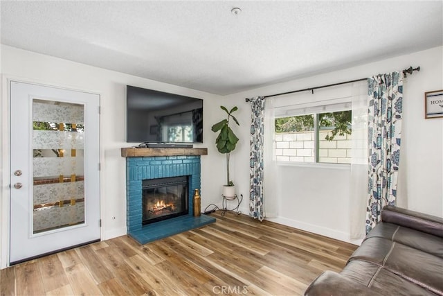 living room featuring a textured ceiling, baseboards, a fireplace, and wood finished floors