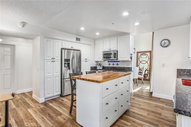 kitchen featuring appliances with stainless steel finishes, baseboards, light wood-type flooring, and wood counters