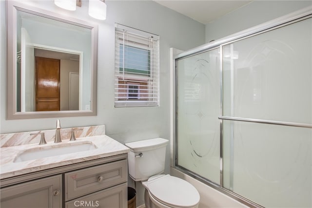 full bathroom featuring vanity, a shower with door, and toilet