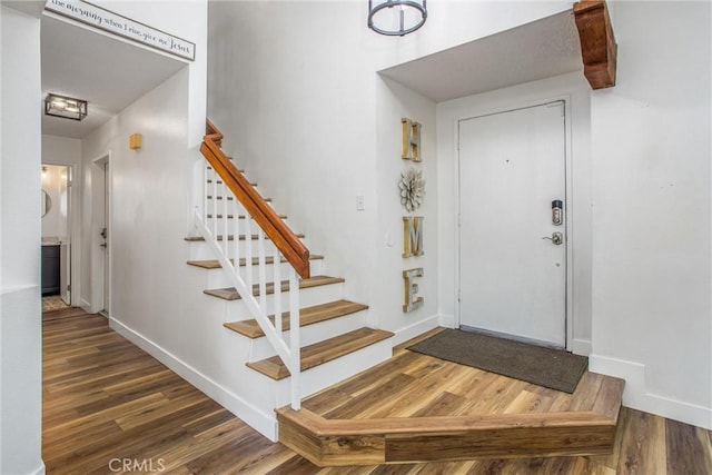 entryway with baseboards, wood finished floors, and stairway