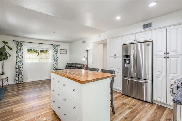 kitchen with visible vents, butcher block countertops, stainless steel refrigerator with ice dispenser, white cabinetry, and light wood finished floors