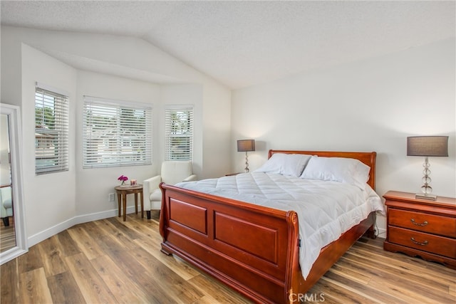bedroom featuring baseboards, vaulted ceiling, and wood finished floors