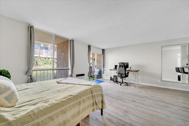 bedroom with baseboards, a textured ceiling, and wood finished floors