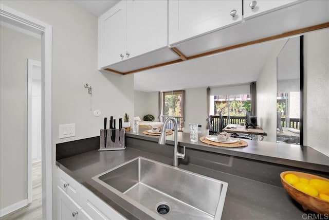 kitchen with white cabinetry, dark countertops, and a sink