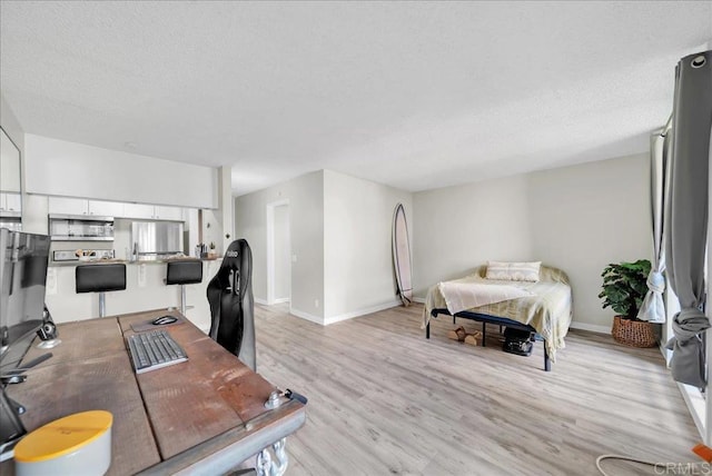 office with light wood-style floors, a textured ceiling, and baseboards