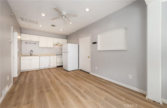 kitchen featuring visible vents, a sink, white appliances, baseboards, and a ceiling fan