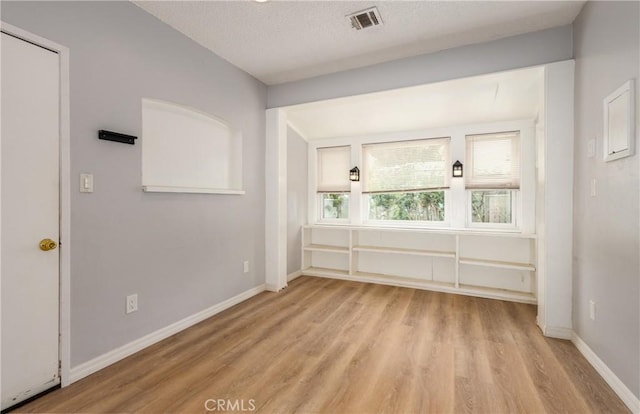 empty room featuring visible vents, light wood finished floors, and baseboards