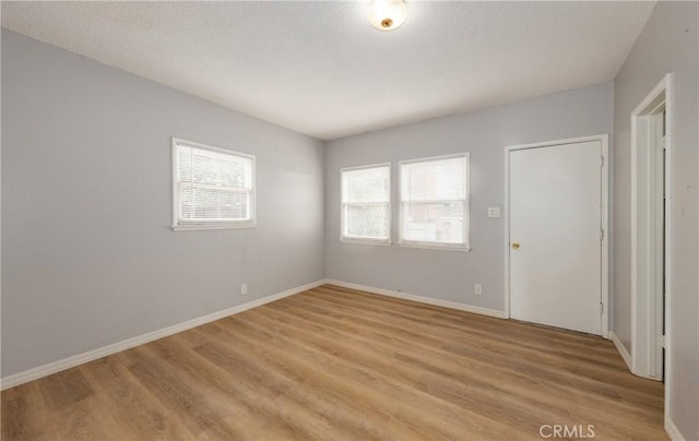 spare room featuring baseboards and light wood-type flooring