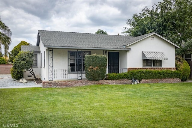 ranch-style home featuring a porch, a shingled roof, and a front lawn