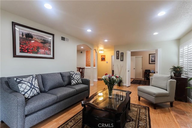 living room with visible vents, arched walkways, recessed lighting, and light wood-type flooring
