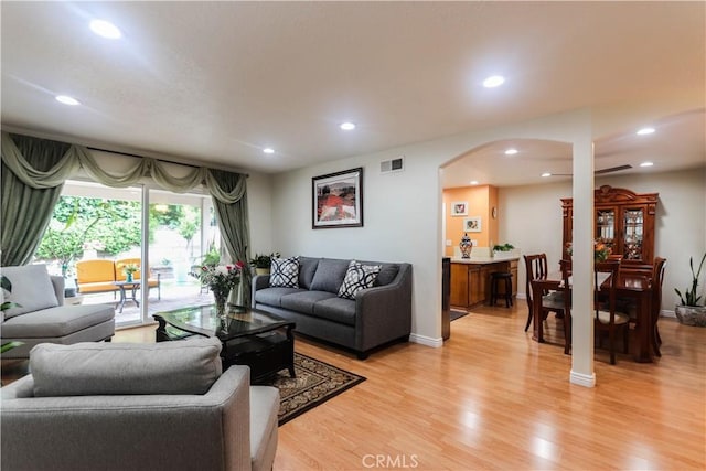 living area with visible vents, arched walkways, light wood-style flooring, and recessed lighting