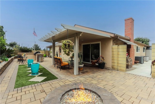 rear view of property featuring a fire pit, a patio, stucco siding, a chimney, and central air condition unit