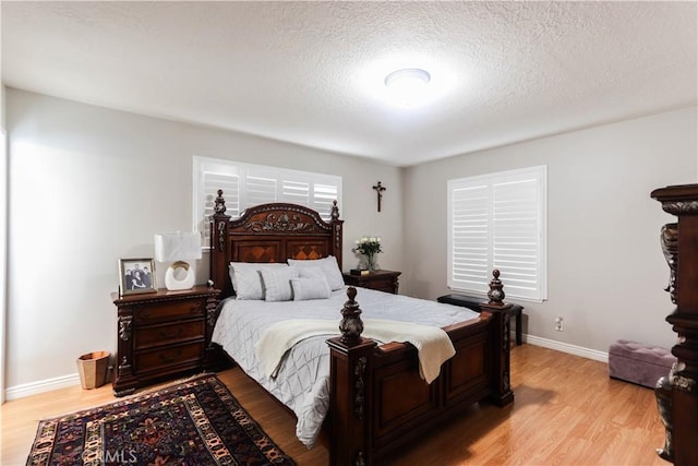 bedroom with a textured ceiling, baseboards, and light wood-style flooring