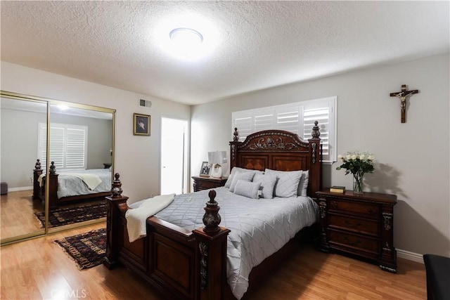 bedroom with a textured ceiling, visible vents, and light wood-type flooring