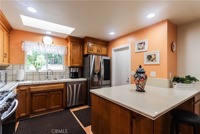 kitchen with stainless steel appliances, tasteful backsplash, a sink, and a peninsula