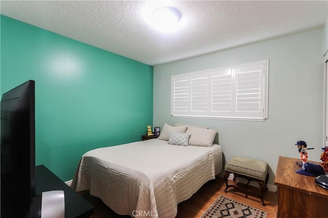 bedroom with a textured ceiling and wood finished floors