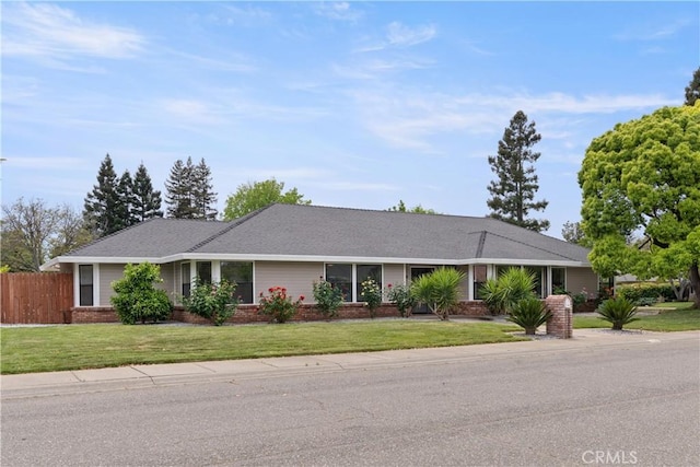 ranch-style house featuring brick siding, fence, and a front yard
