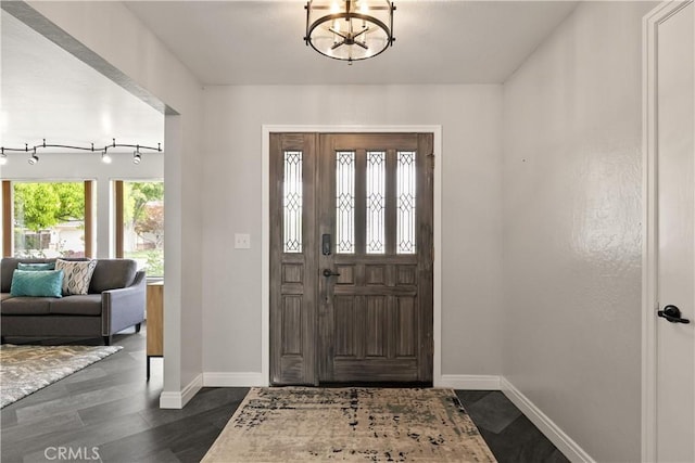 foyer featuring an inviting chandelier, baseboards, and dark wood-type flooring