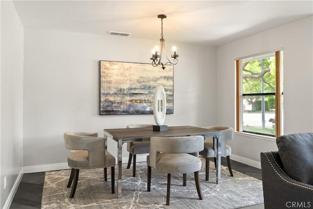 dining space featuring visible vents, baseboards, wood finished floors, and a chandelier